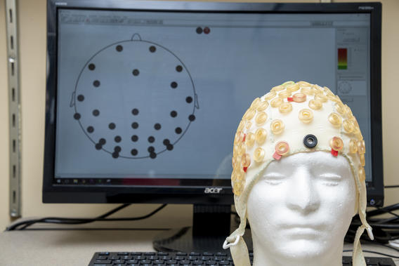 EEG cap on a fake head with a computer in the background